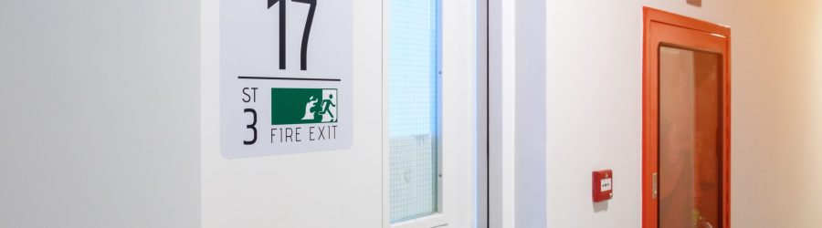 Fire extinguisher system on the wall with Fire Exit door sign for emergency. Stairwell fire for escape in building or apartment